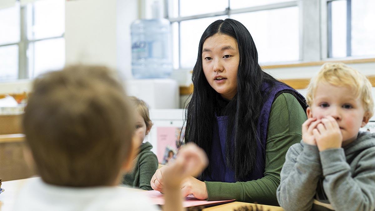 一位妇女和一群小孩坐在一张桌子旁.